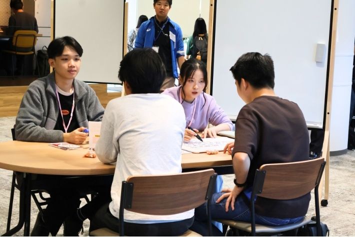テーブルを囲んで会話する学生たち